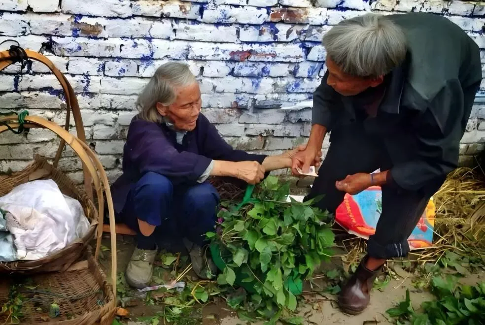 Two elders sharing vegetables beside old baskets.
